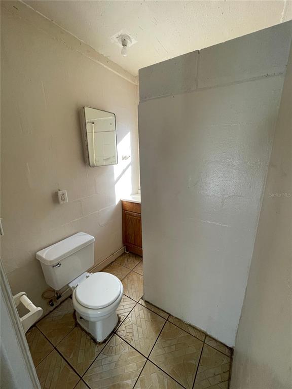 A small bathroom features a white toilet, a wall-mounted mirror, and tiled flooring — 131 B STREET UNIT 3, LAKE WALES, FL