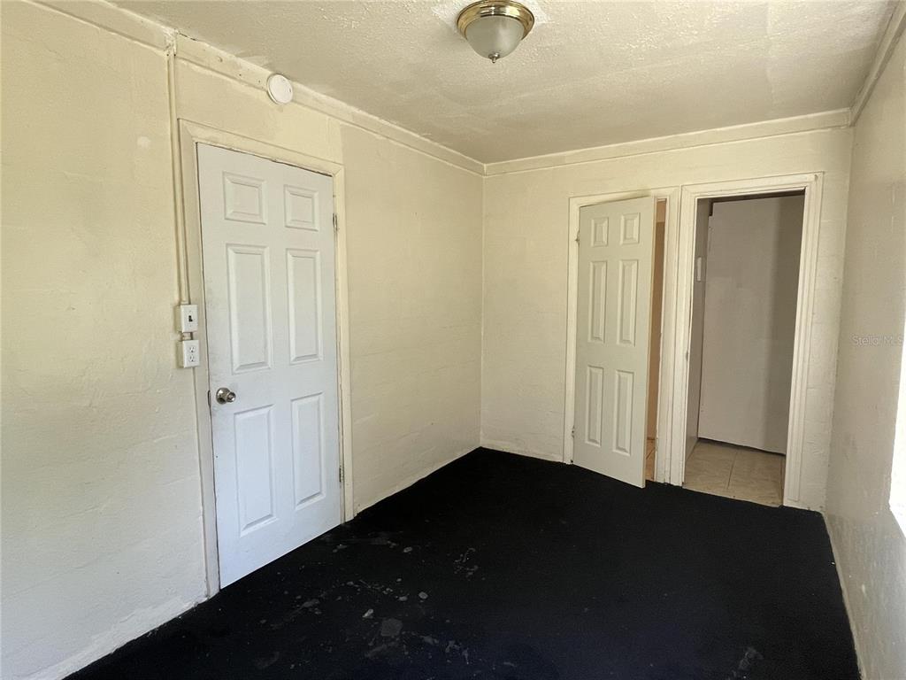 An interior room with white walls, black carpeting, two white doors, and a ceiling light — 131 B STREET UNIT 3, LAKE WALES, FL