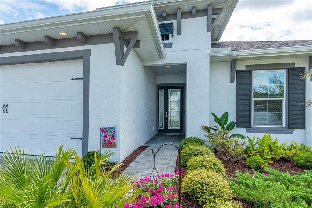The exterior of a white house features a garage, a paved walkway, and front landscaping — 268 MOSAIC BOULEVARD, DAYTONA BEACH, FL