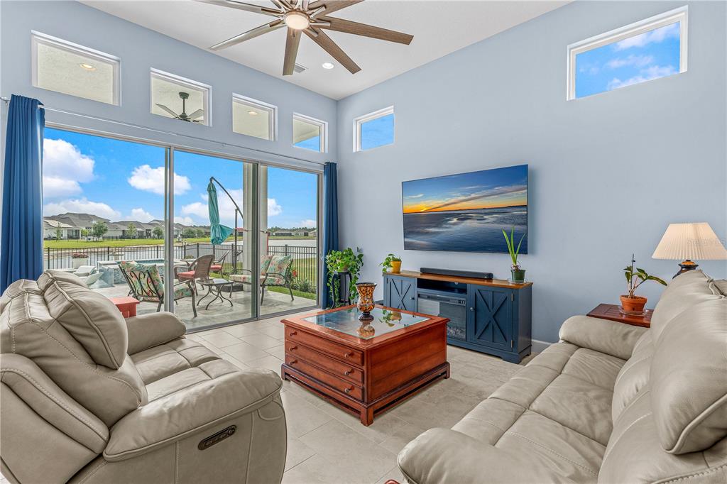 A living room with light blue walls, two leather sofas, a coffee table, and sliding doors — 268 MOSAIC BOULEVARD, DAYTONA BEACH, FL