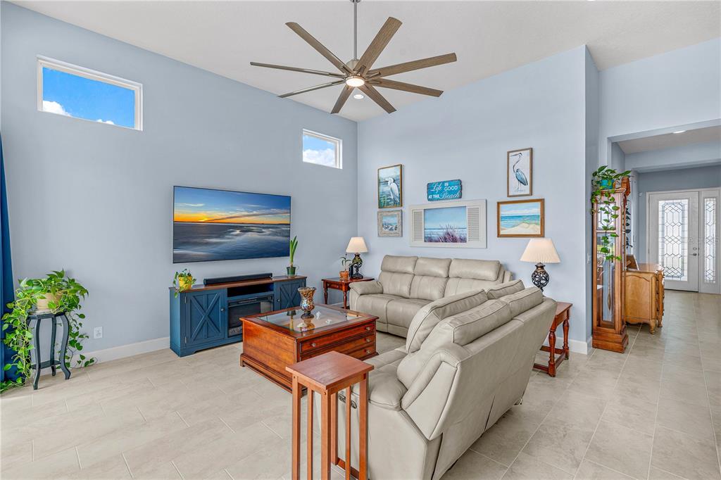 A living room features light blue walls, a ceiling fan, a television, and beige furniture — 268 MOSAIC BOULEVARD, DAYTONA BEACH, FL