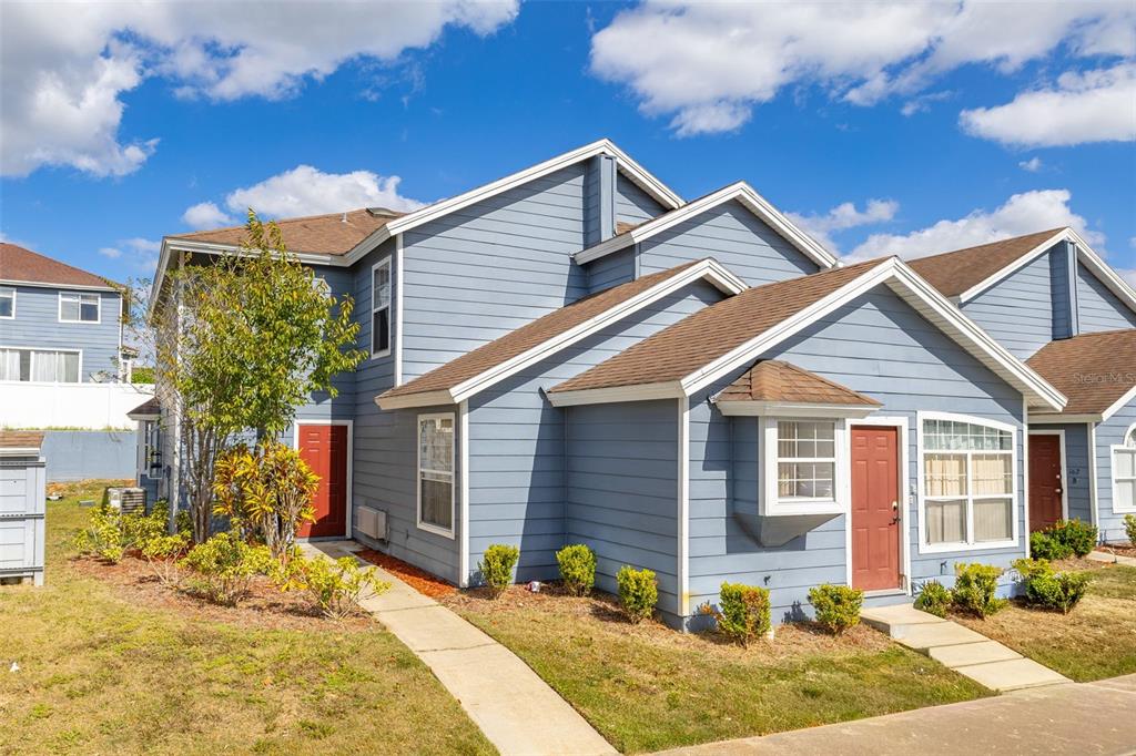 A two-story blue house with a brown shingled roof and two red front doors — 142 MANGO DRIVE, DAVENPORT, FL