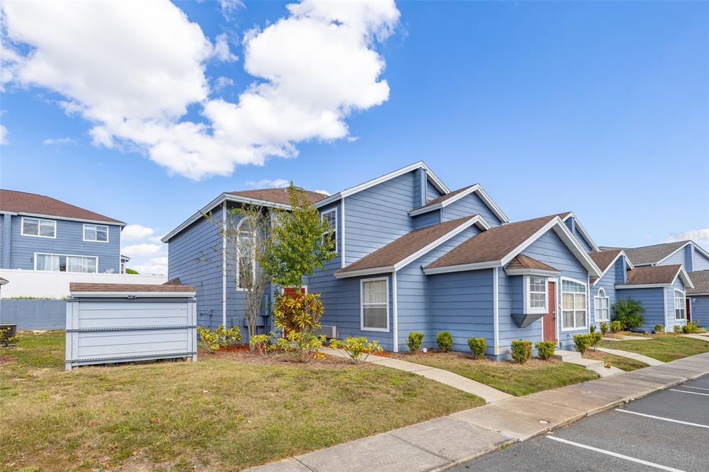 A blue two-story townhouse with a brown roof and a small front yard — 142 MANGO DRIVE, DAVENPORT, FL