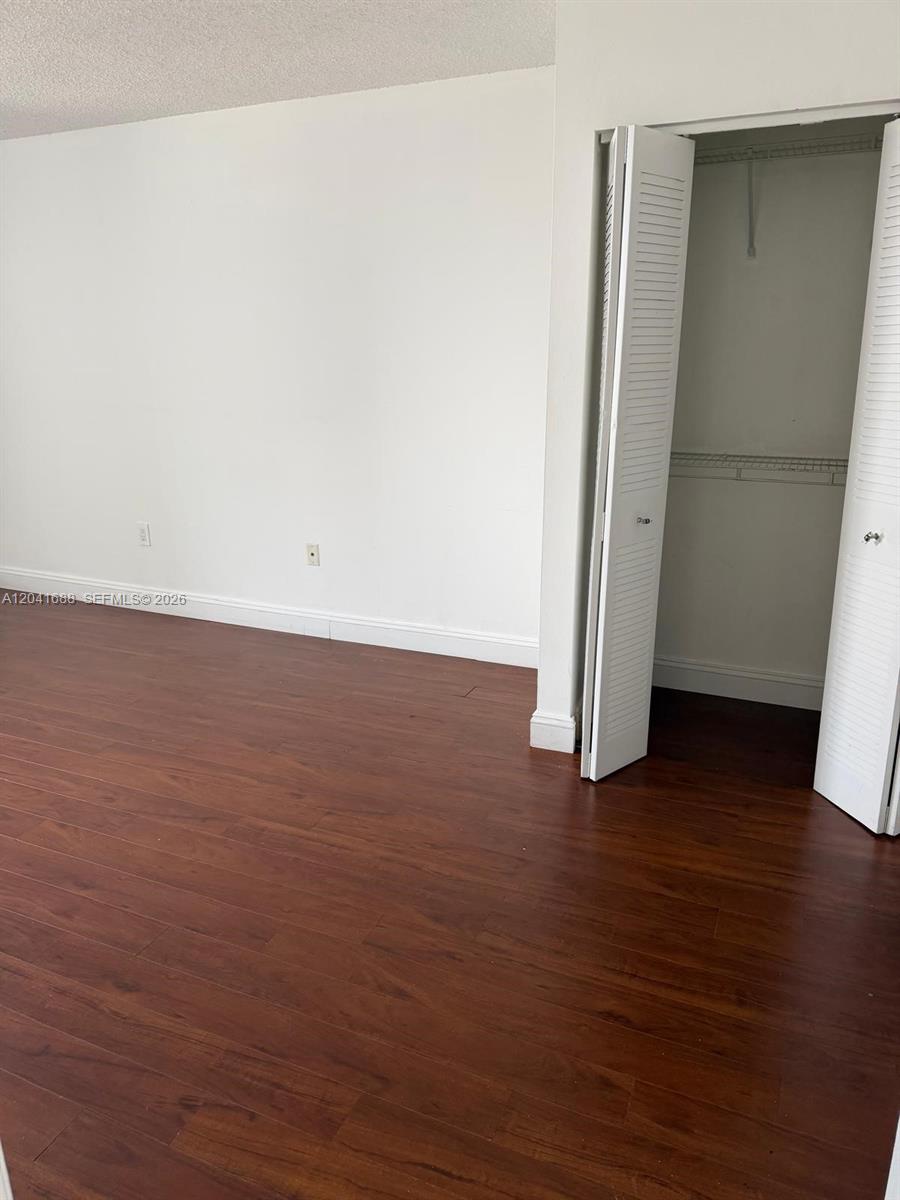 An empty room features dark wood-look flooring, white walls, and an open closet — 800 N Miami Ave # E1402, Miami FL 33136, MIAMI, FL
