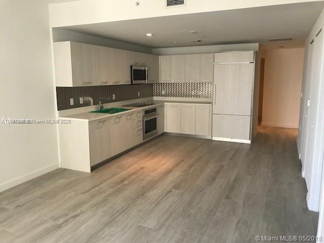 A modern kitchen features light wood cabinetry, stainless steel appliances, and gray wood-look flooring — 55 SW 9th St # 2510, Miami FL 33130, MIAMI, FL