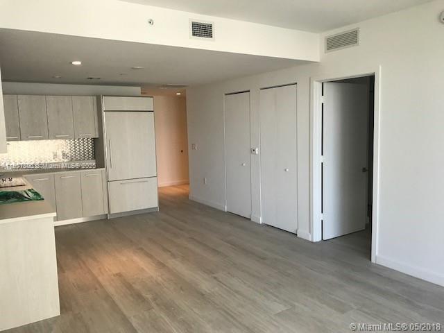 A modern kitchen features light wood cabinetry, stainless steel appliances, and light-colored wood flooring — 55 SW 9th St # 2510, Miami FL 33130, MIAMI, FL