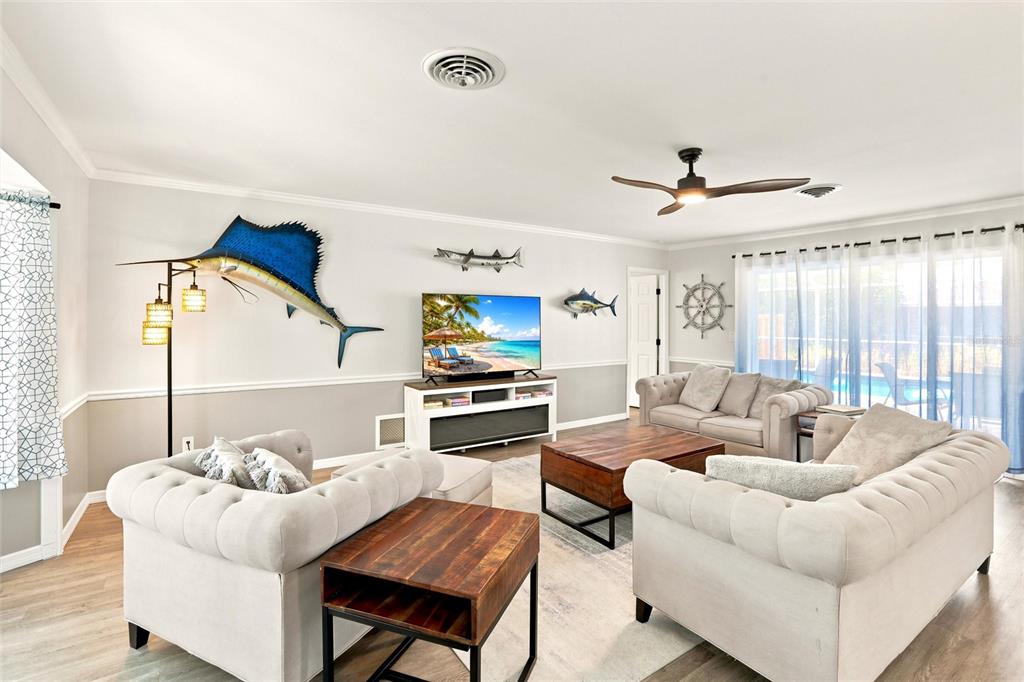 A living room features two tufted sofas, a television, and nautical wall decor — 1795 ELINOR PLACE, ENGLEWOOD, FL