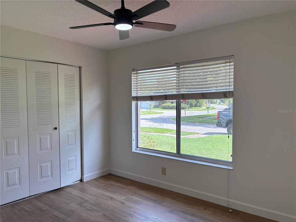 A bedroom features wood-look flooring, a ceiling fan, a closet, and a window with blinds — 4824 GALLANT LANE, ORLANDO, FL