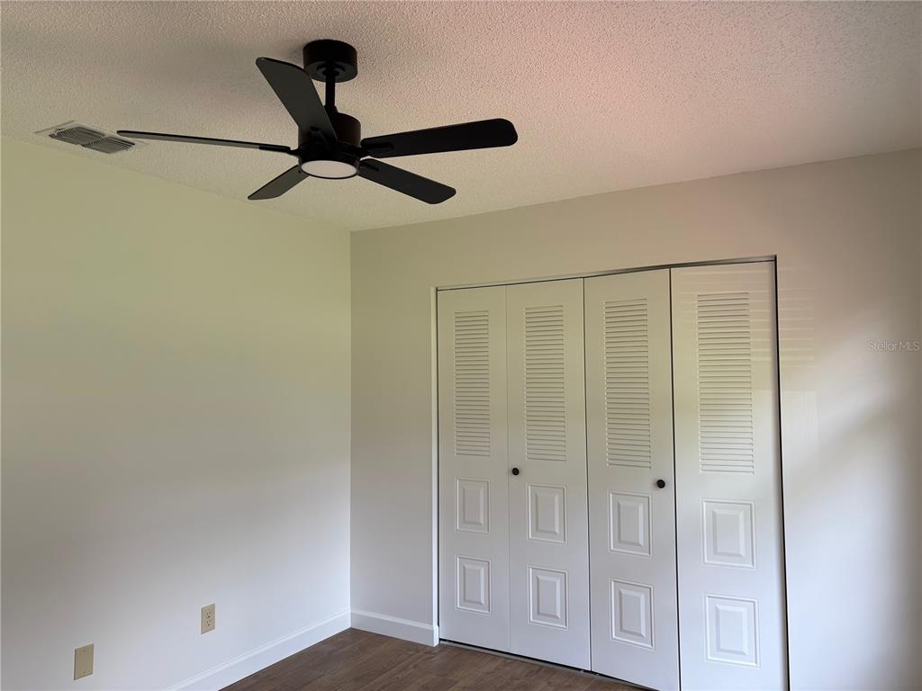 A bedroom features a black ceiling fan, white louvered closet doors, and wood-look flooring — 4824 GALLANT LANE, ORLANDO, FL