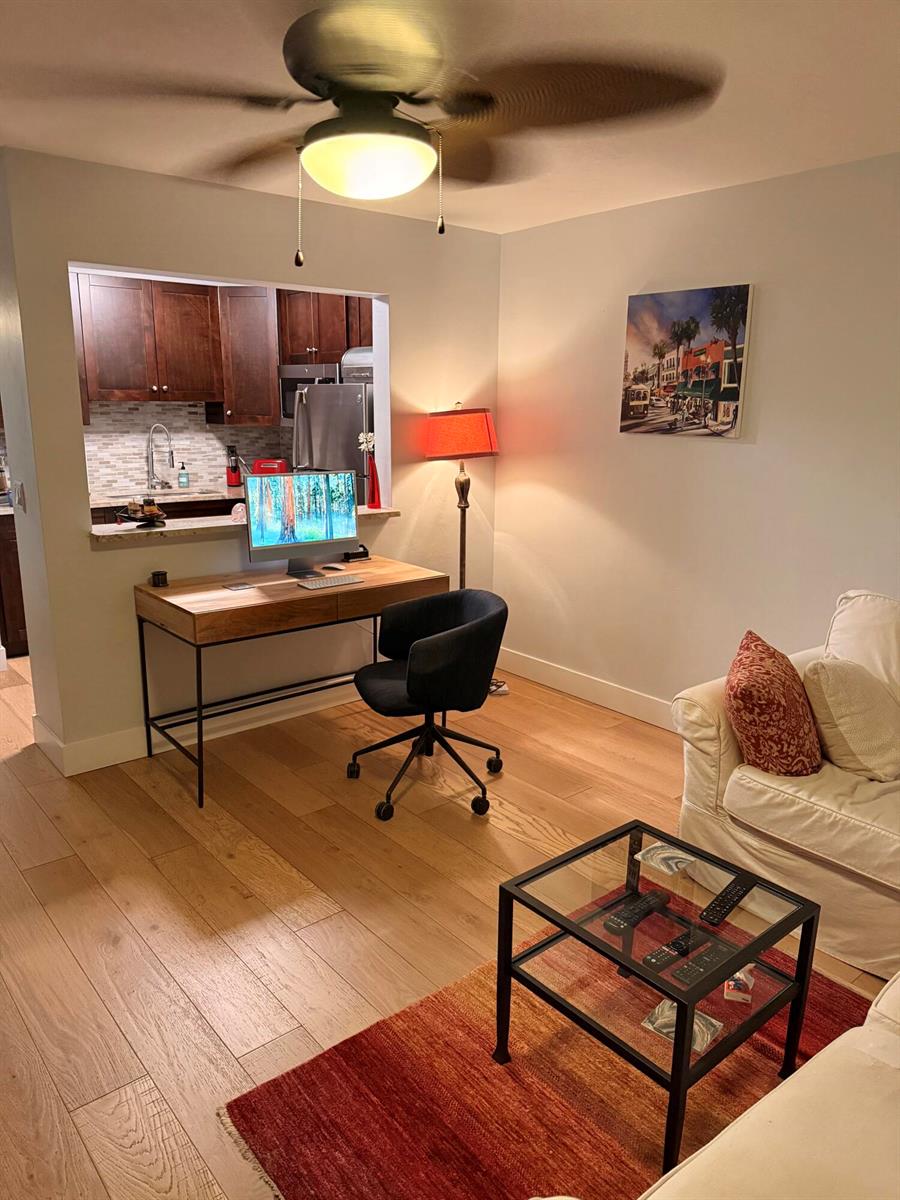 A living room features a desk, a floor lamp, a glass coffee table, and wood flooring — 2920 Cynthia Lane # 107, FL 33461, FL