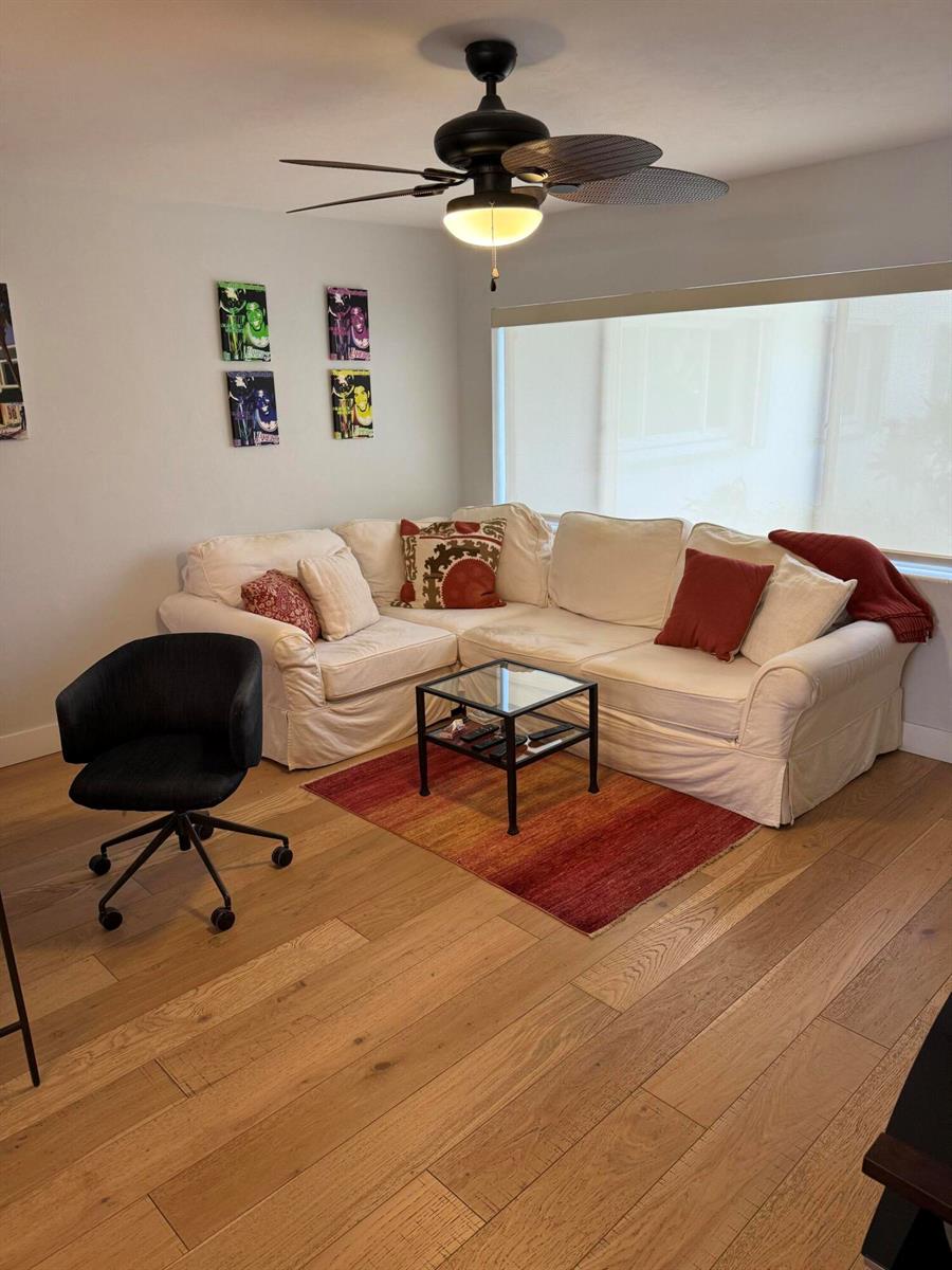 A living room features a white sectional sofa, a glass coffee table, and wood flooring — 2920 Cynthia Lane # 107, FL 33461, FL