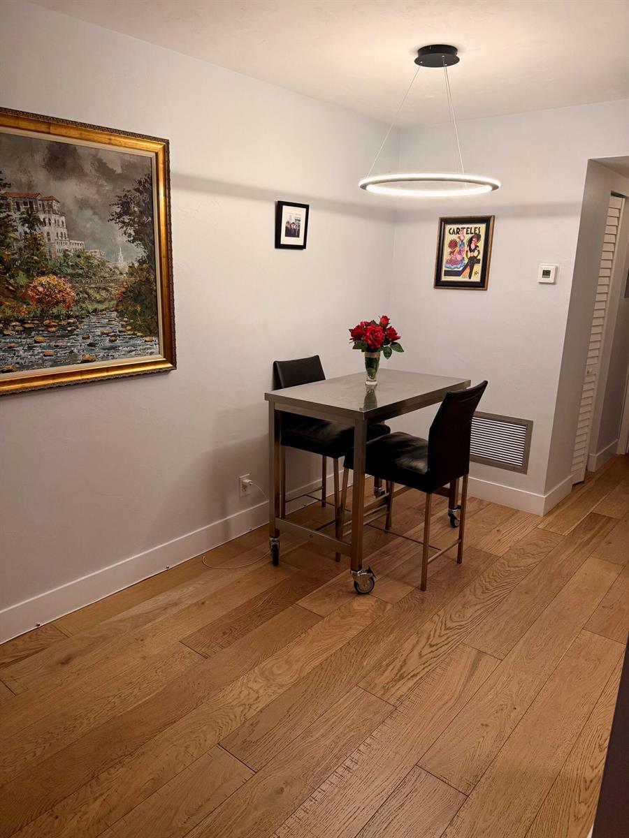 A small dining area features a metal table with two chairs, a pendant light, and artwork — 2920 Cynthia Lane # 107, FL 33461, FL