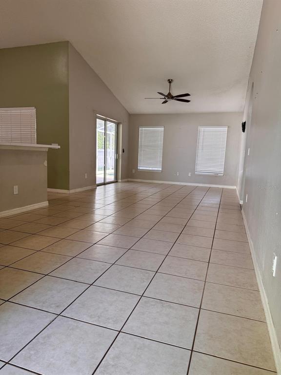 An open-concept living area features light-colored tile flooring, vaulted ceilings, and a ceiling fan — 40045 PALM STREET, LADY LAKE, FL