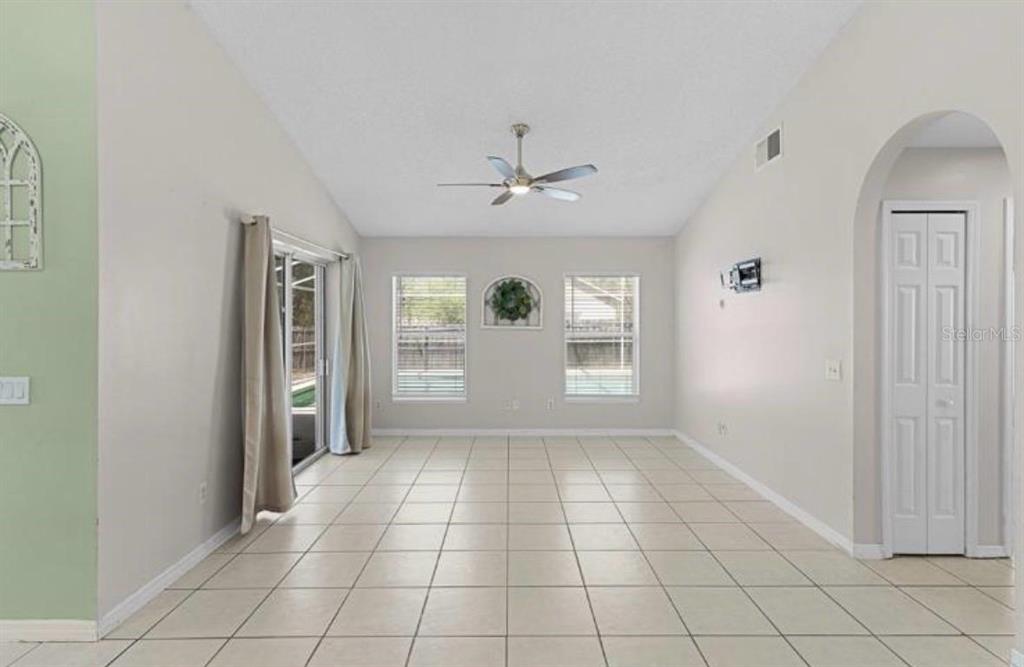A bright living room features light tile flooring, a ceiling fan, and sliding glass doors — 40045 PALM STREET, LADY LAKE, FL