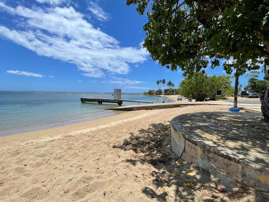 A sandy beach features a concrete pier extending into the ocean under a blue sky — K5 VILLAS DE PLAYA II UNIT K5, DORADO, PR