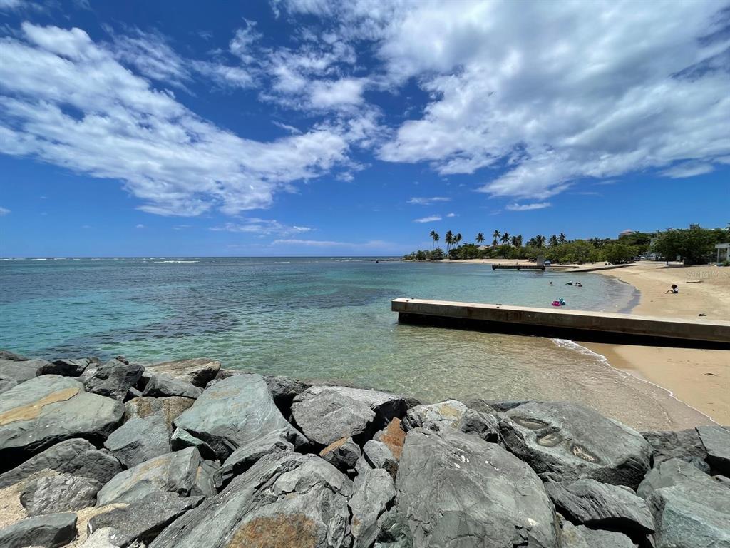 A rocky shoreline overlooks a sandy beach with a concrete pier extending into the ocean — K5 VILLAS DE PLAYA II UNIT K5, DORADO, PR