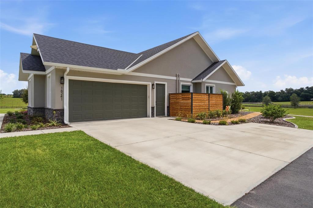 A stone path leads to the back patio of a single-story house with landscaping — 16241 SE 150TH AVENUE, WEIRSDALE, FL