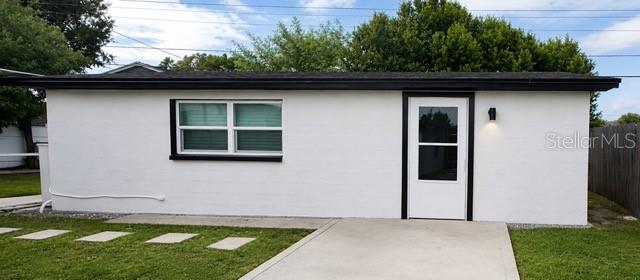 A white, single-story building with a black roof, black window trim, and a glass-paneled door — 4533 W FERN STREET, TAMPA, FL