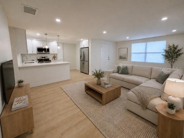 A living room with light wood floors, a sectional sofa, and an open-concept kitchen — 4533 W FERN STREET, TAMPA, FL