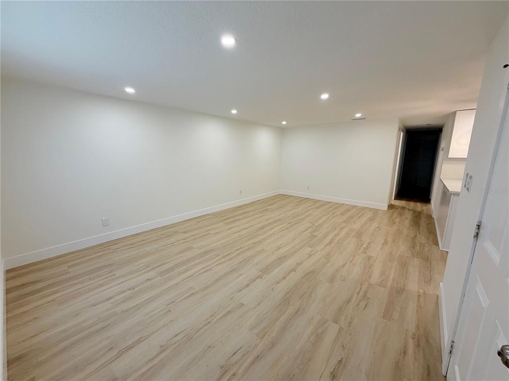 A bright, empty room features light wood-look flooring, white walls, and recessed ceiling lighting — 4533 W FERN STREET, TAMPA, FL