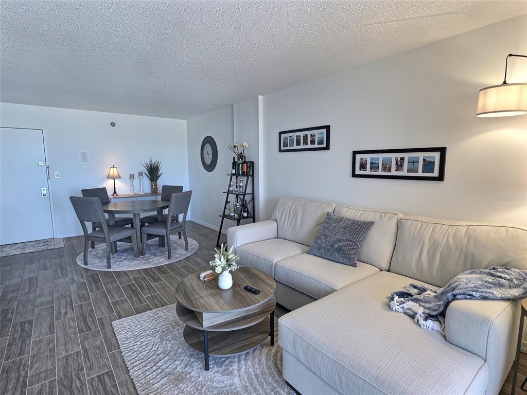 A living and dining area features a sectional sofa, round coffee table, and dining set — 3006 CARING WAY UNIT 602, PORT CHARLOTTE, FL