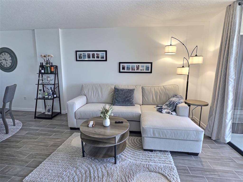 A living room features a beige sectional sofa, a round coffee table, and a floor lamp — 3006 CARING WAY UNIT 602, PORT CHARLOTTE, FL