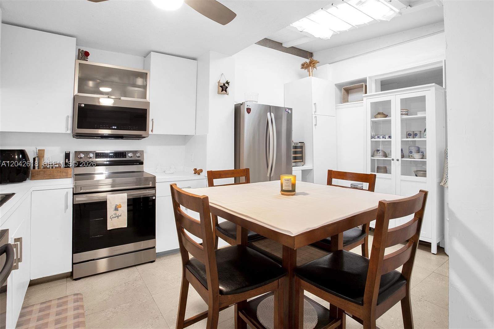 A kitchen features white cabinetry, stainless steel appliances, and a wooden dining table with chairs — 9675 NW 26th Pl # 5, Sunrise FL 33322, SUNRISE, FL