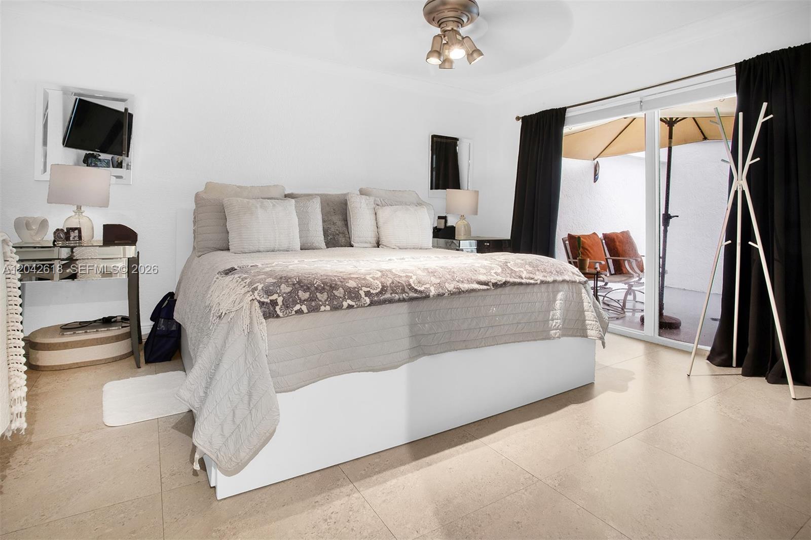 A bedroom features a bed with grey bedding, tile floors, and sliding doors to a patio — 9675 NW 26th Pl # 5, Sunrise FL 33322, SUNRISE, FL