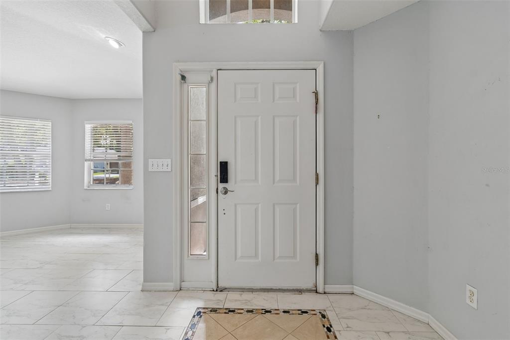 A white front door with a side window light opens into a tiled entryway — 4643 DUNNIE DRIVE, TAMPA, FL