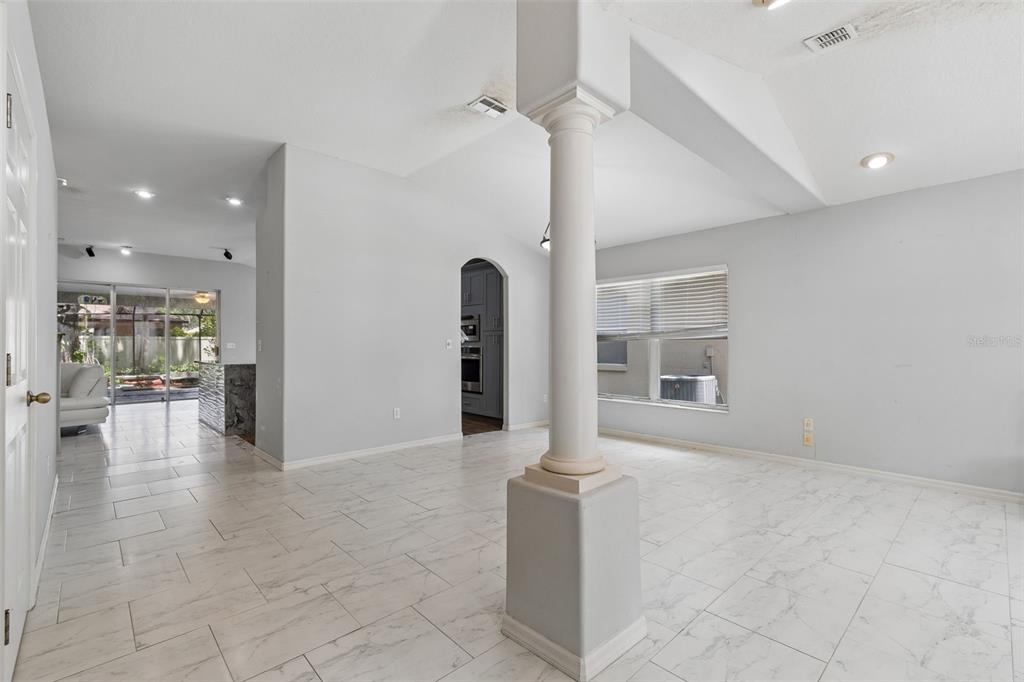 A bright, open-concept living area features white marble-look tile floors and a central support column — 4643 DUNNIE DRIVE, TAMPA, FL