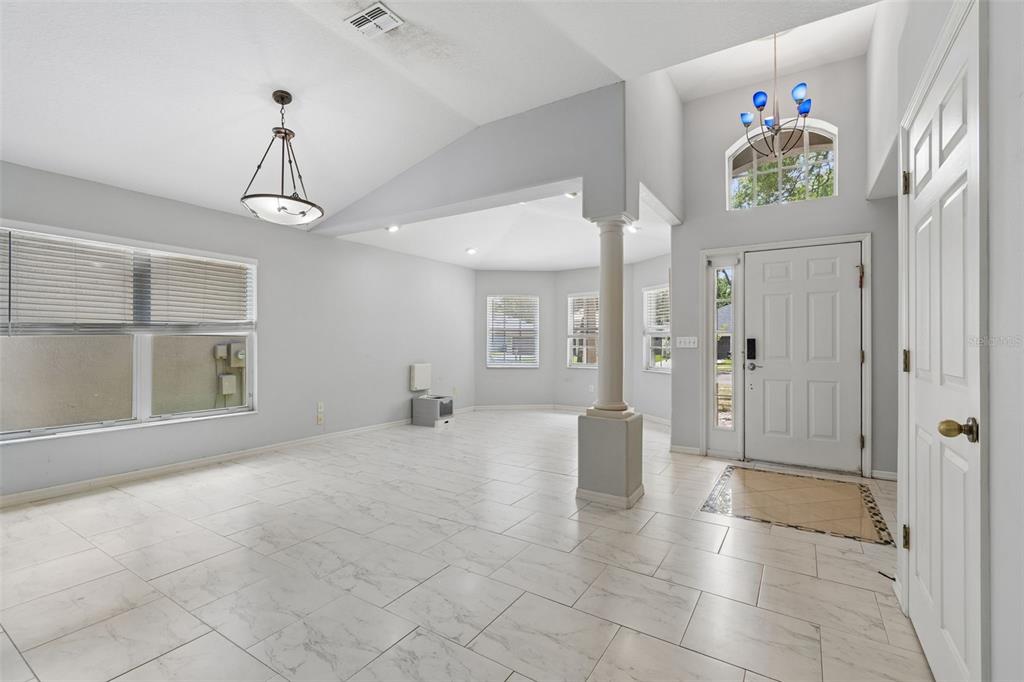 A bright, open-concept living area features white tile flooring, a vaulted ceiling, and a column — 4643 DUNNIE DRIVE, TAMPA, FL