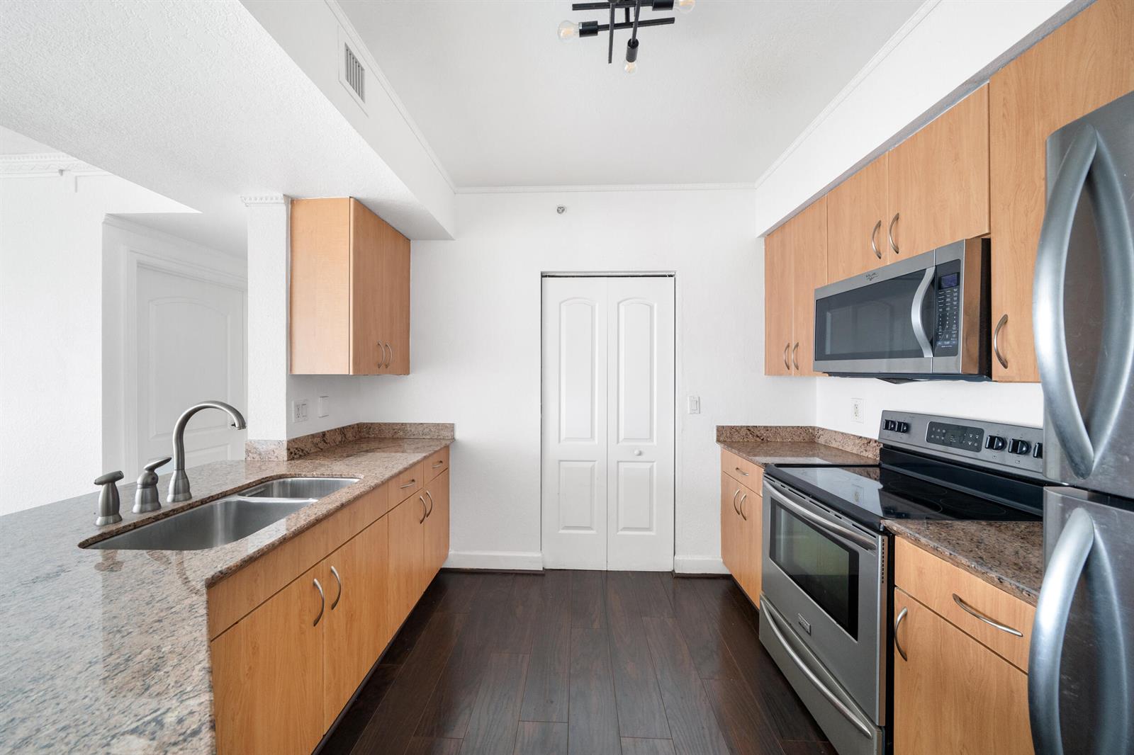 A kitchen with light wood cabinets, granite countertops, stainless steel appliances, and dark wood flooring — 1830 Radius Drive # 405, Hollywood FL 33020, HOLLYWOOD, FL