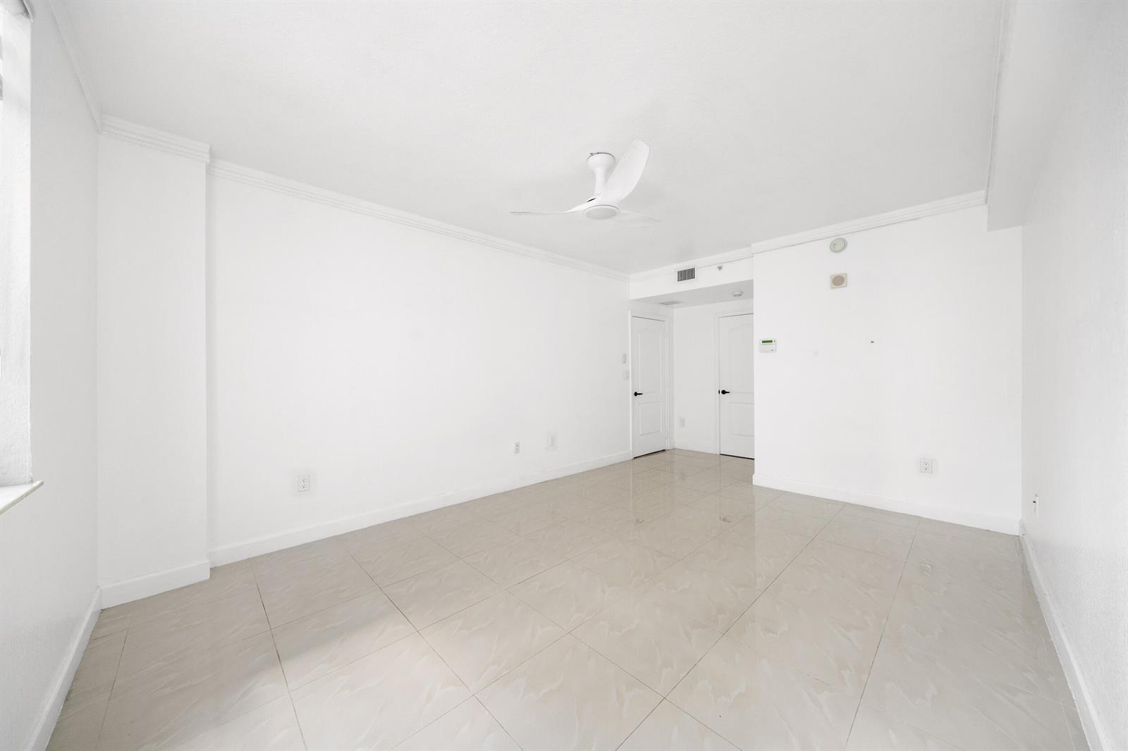 An empty room features white walls, a ceiling fan, and light-colored tile flooring — 1830 Radius Drive # 405, Hollywood FL 33020, HOLLYWOOD, FL