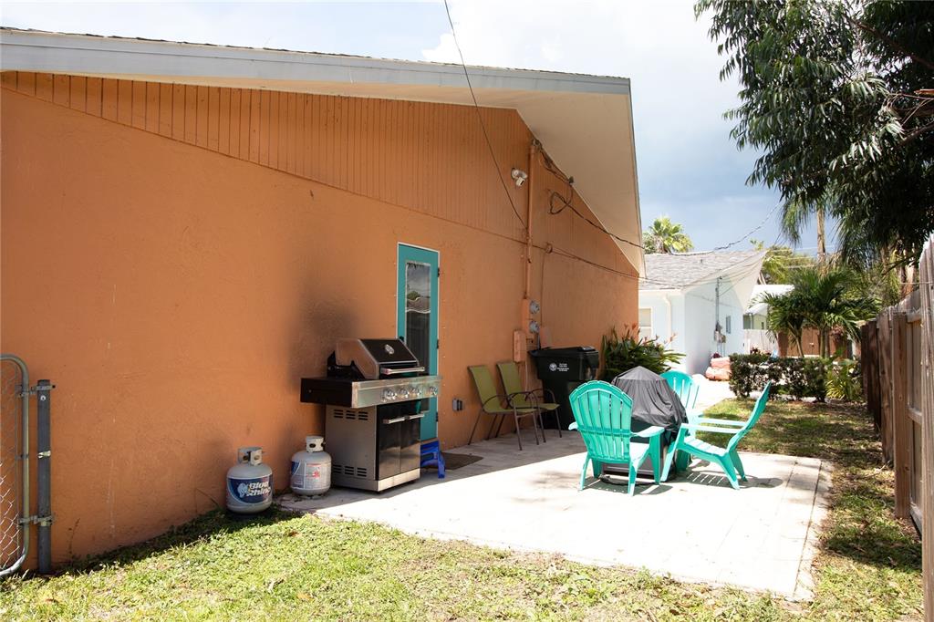 A patio area features a grill, outdoor chairs, and a propane tank against a house — 1635 GLADYS STREET UNIT 2, LARGO, FL