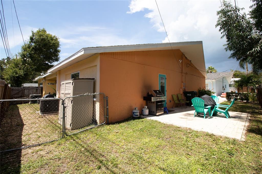 A backyard view shows a peach-colored house exterior with a patio, grill, and outdoor furniture — 1635 GLADYS STREET UNIT 2, LARGO, FL