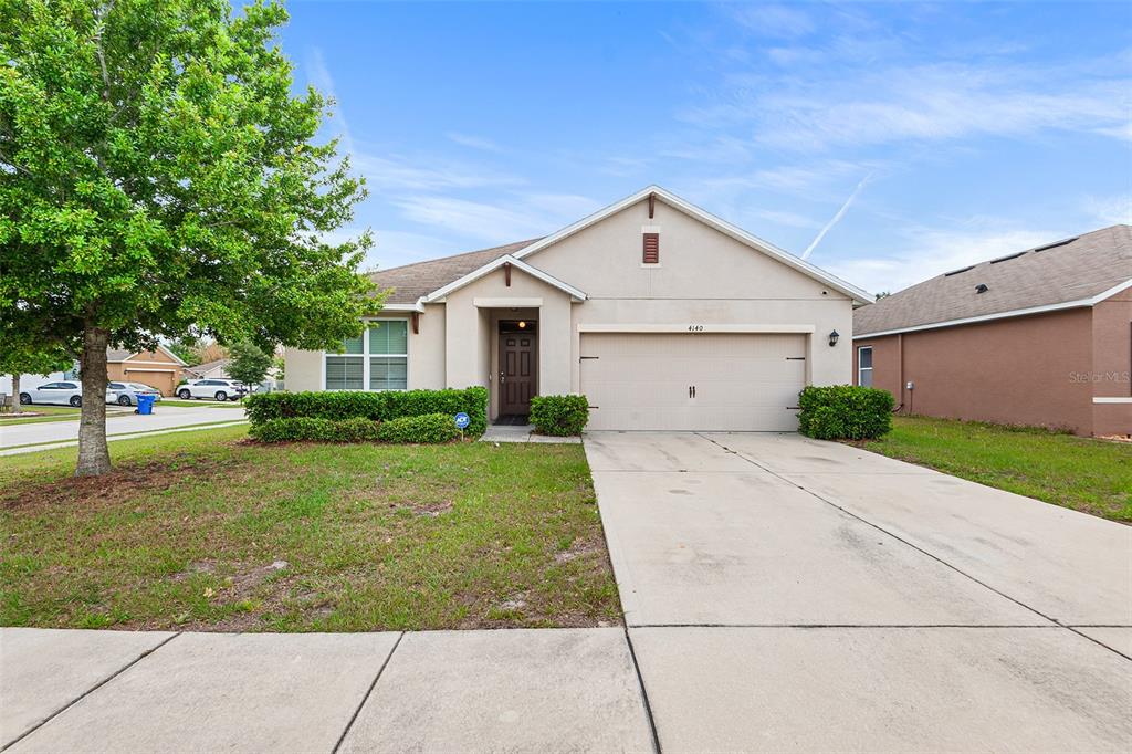 A single-story suburban house with a beige stucco exterior, a two-car garage, and a lawn — 4140 SOPHIA BOULEVARD, WINTER HAVEN, FL
