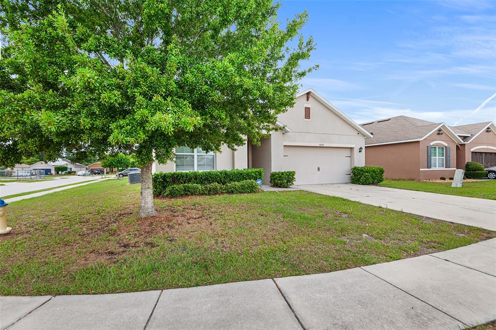 A single-story suburban house with a two-car garage, a front lawn, and a large tree — 4140 SOPHIA BOULEVARD, WINTER HAVEN, FL