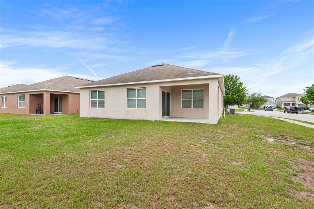 The exterior view shows the rear of a beige stucco house with a covered patio — 4140 SOPHIA BOULEVARD, WINTER HAVEN, FL