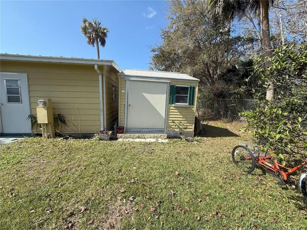 A small yellow shed sits attached to the side of a house in a yard — 15 WILDERNESS DRIVE, LAKE PANASOFFKEE, FL
