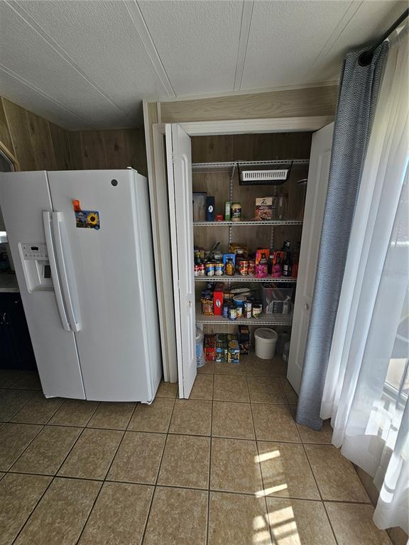 A white side-by-side refrigerator stands next to an open pantry with wire shelving — 15 WILDERNESS DRIVE, LAKE PANASOFFKEE, FL