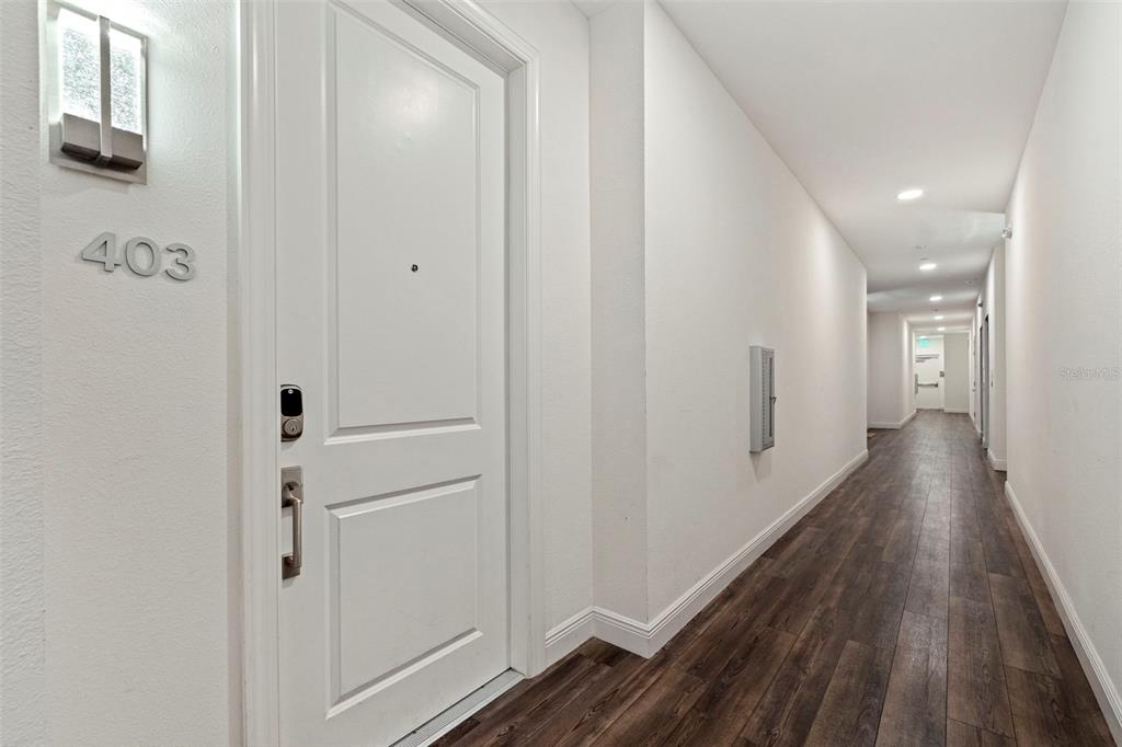 A white apartment door labeled 403 opens into a long hallway with wood-look flooring — 644 3RD AVENUE S UNIT 403, ST PETERSBURG, FL