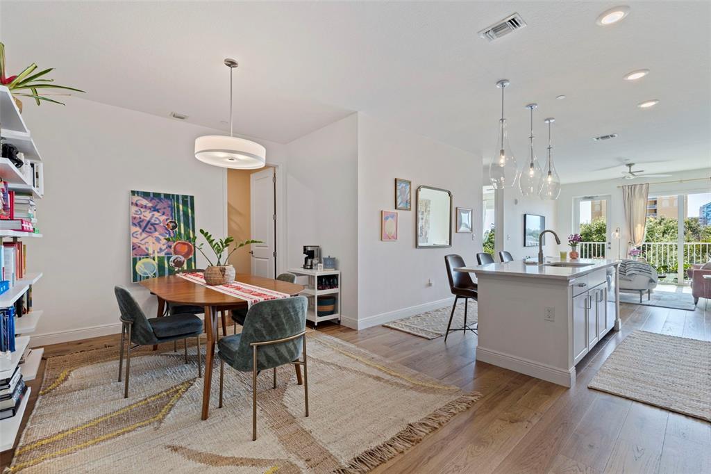 A dining area with a wooden table and chairs sits adjacent to a modern kitchen — 644 3RD AVENUE S UNIT 403, ST PETERSBURG, FL