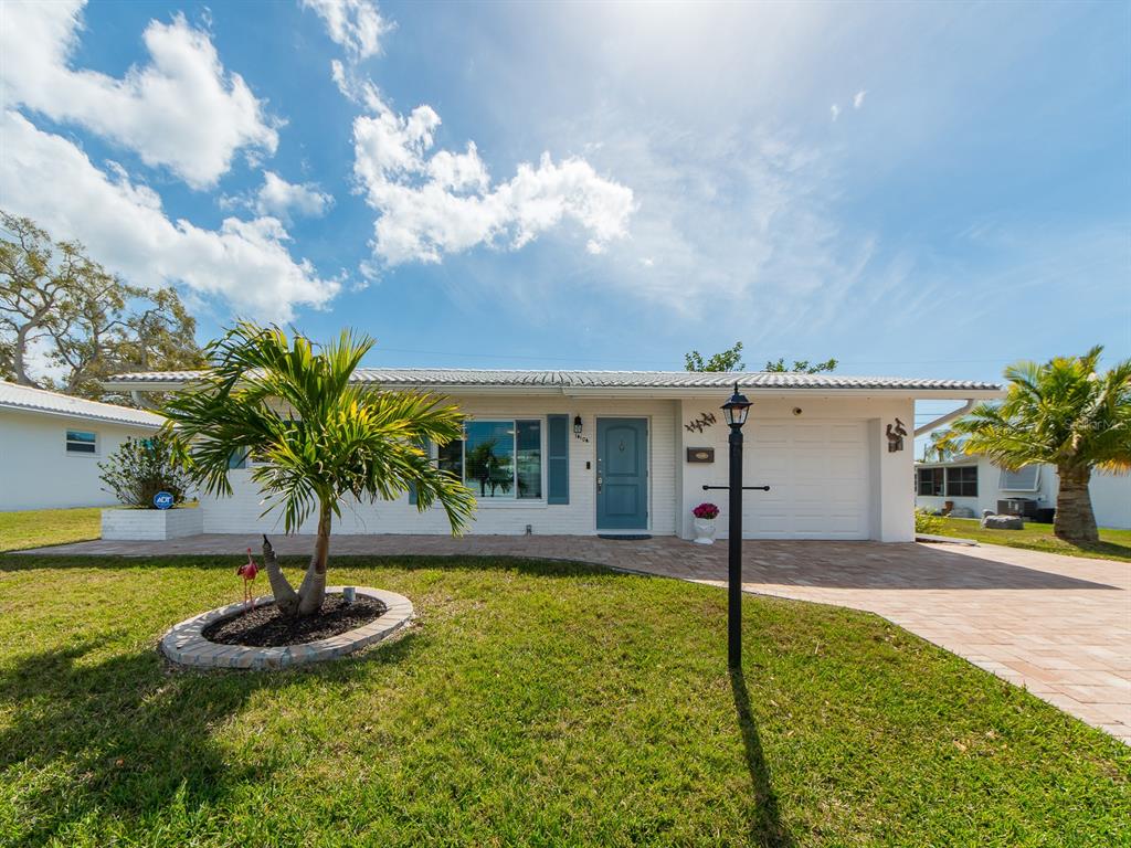 A white brick house with a blue front door and a paved driveway under a sky — 14104 88TH AVENUE, SEMINOLE, FL