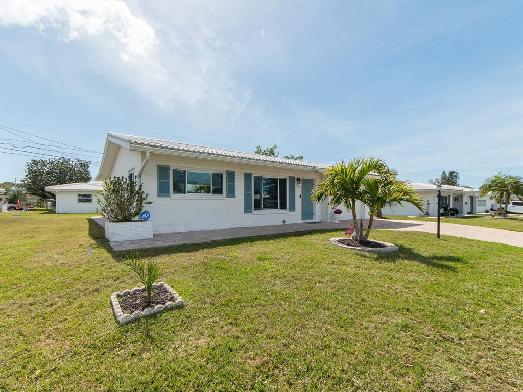 A white brick single-story house features blue shutters, a tiled roof, and a palm tree — 14104 88TH AVENUE, SEMINOLE, FL