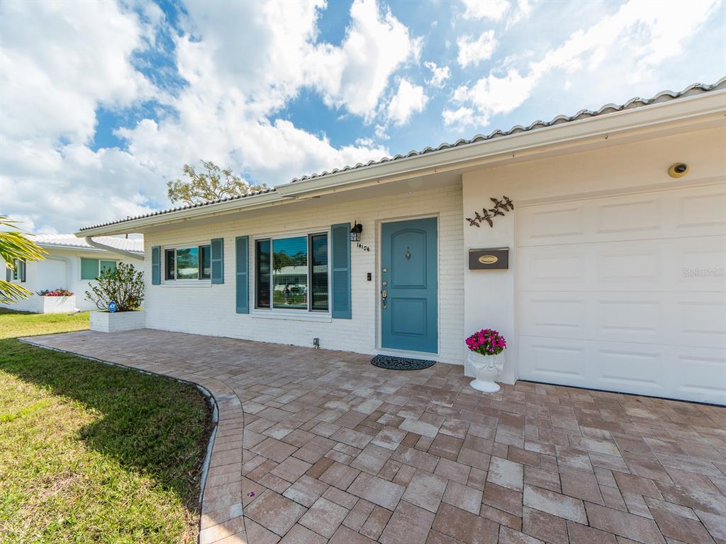 A white brick house features a blue front door, blue shutters, and a paver driveway — 14104 88TH AVENUE, SEMINOLE, FL