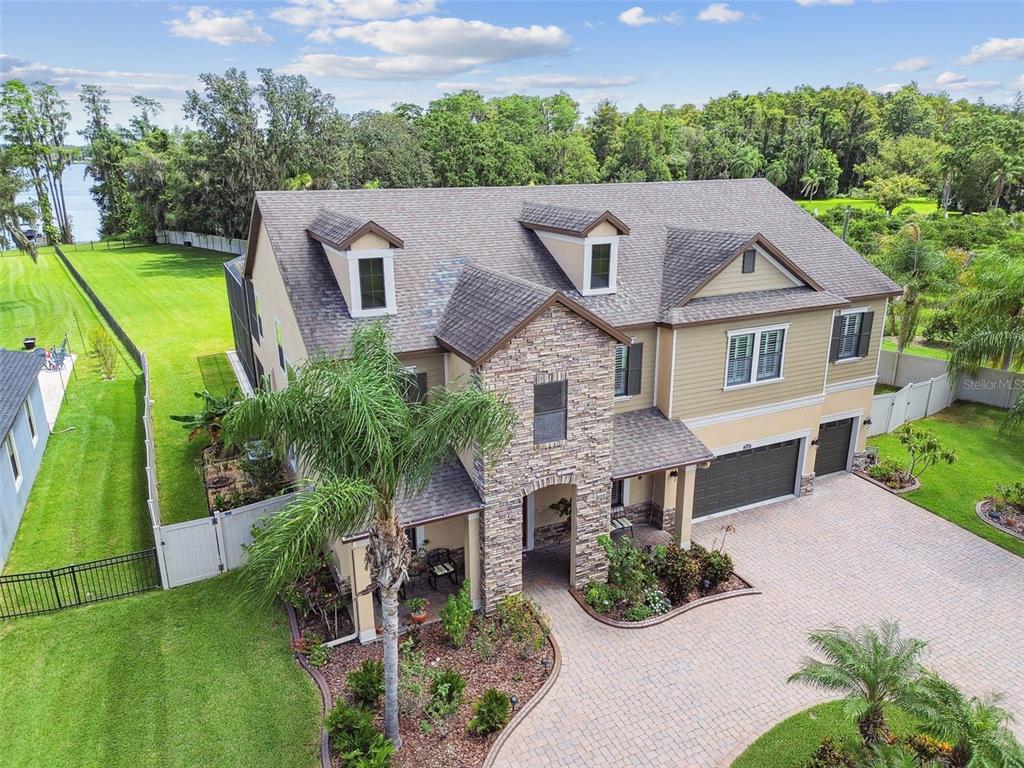 An aerial view of a two-story house with stone siding, a paver driveway, and landscaping — 2566 LAKE MANOR DRIVE, LAND O LAKES, FL