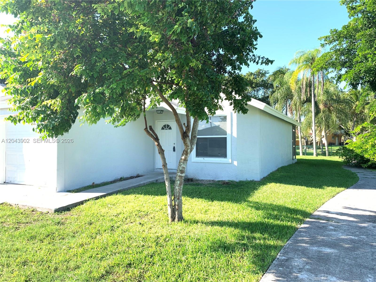 A light-colored single-story house features a front door, a window, and a tree — 848 SW 10th St, Florida City FL 33034, FLORIDA CITY, FL