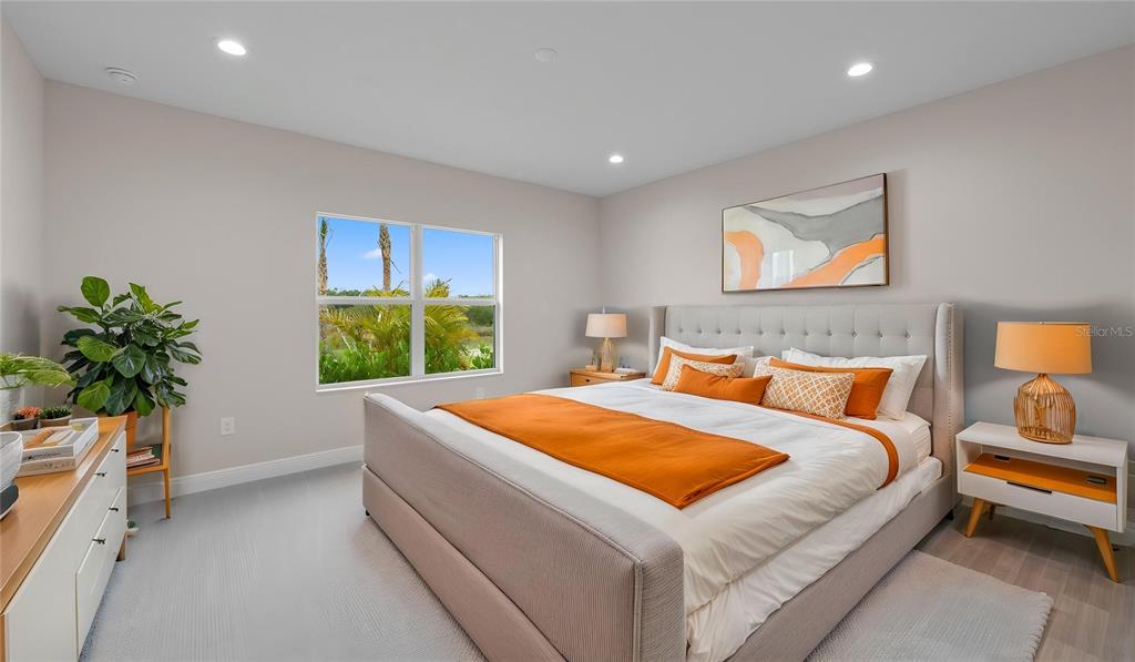 A bedroom features a tufted bed, orange accents, a window with outdoor views, and furniture — 2937 HERITAGE PINES DRIVE, FORT MYERS, FL