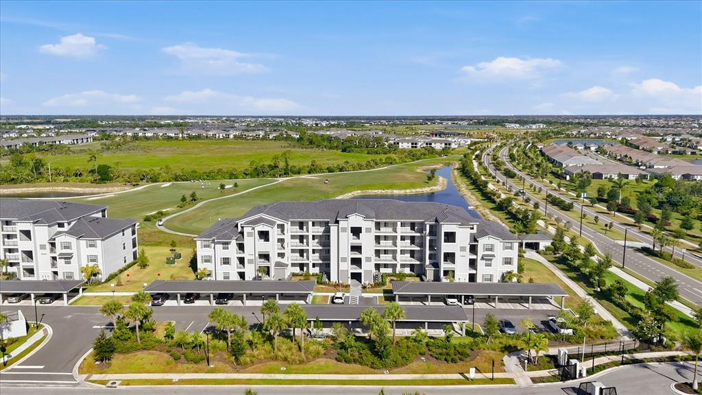 An aerial view shows a multi-story apartment building with covered parking and surrounding landscaping — 17655 OPAL SAND DRIVE UNIT 107, VENICE, FL