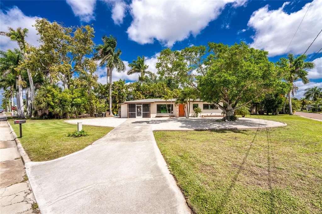 A single-story house with a concrete driveway, a screened porch, and mature palm trees — 312 MCGREGOR STREET, PUNTA GORDA, FL